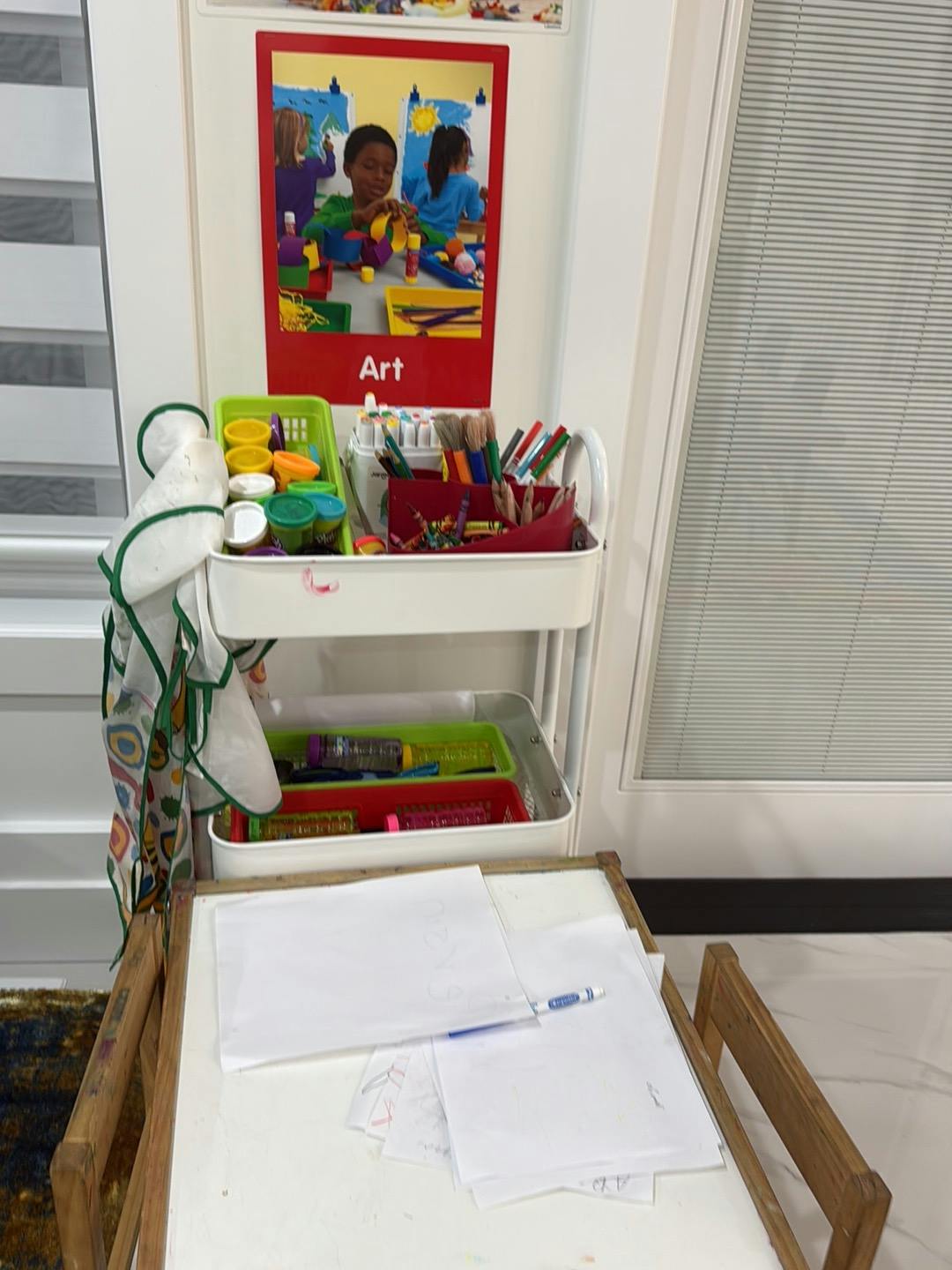 Art supply cart with paper and pens on a small desk