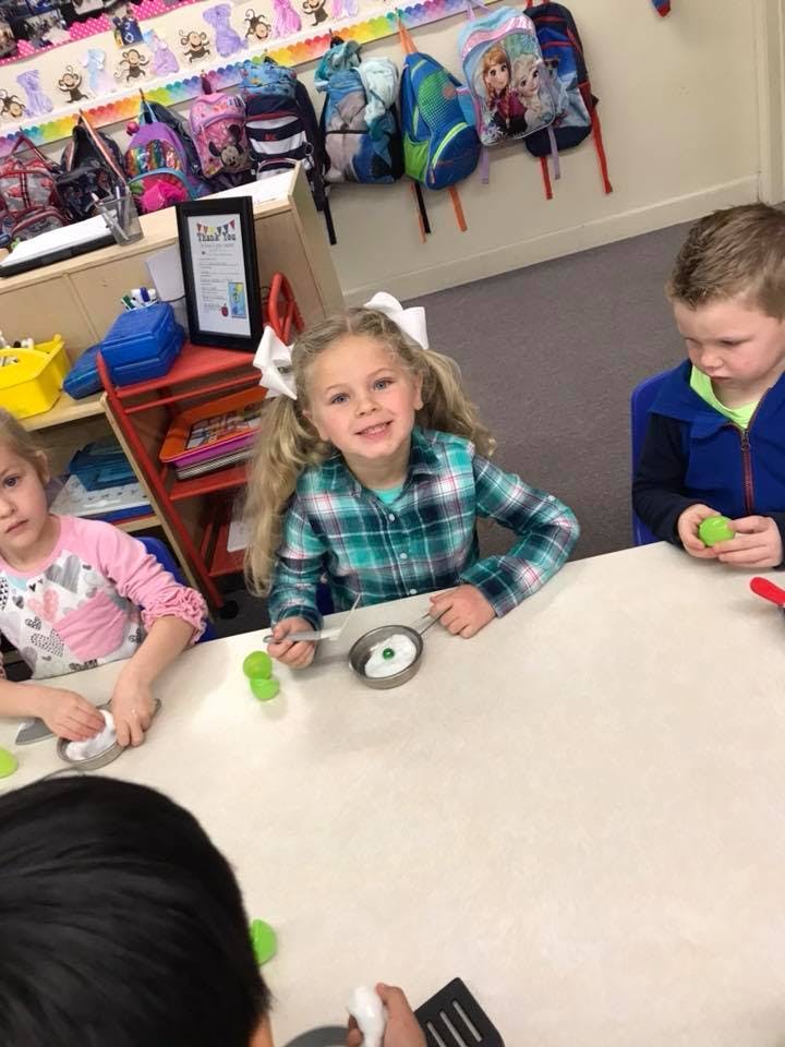 Three children playing with toy food at a table