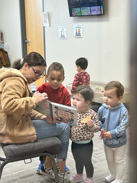 Person reading a book to three children