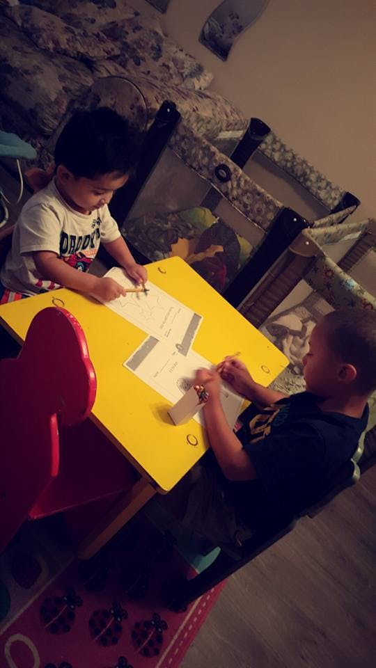 Two children drawing at a yellow table