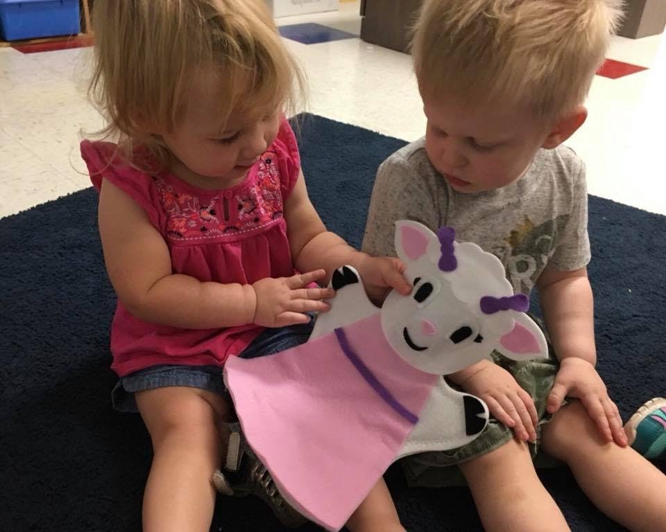 Two children playing with a lamb puppet