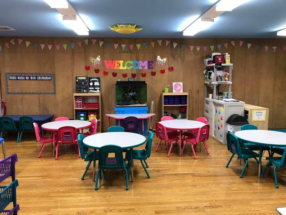Classroom with small tables and chairs, a fish tank, and a "WELCOME" sign