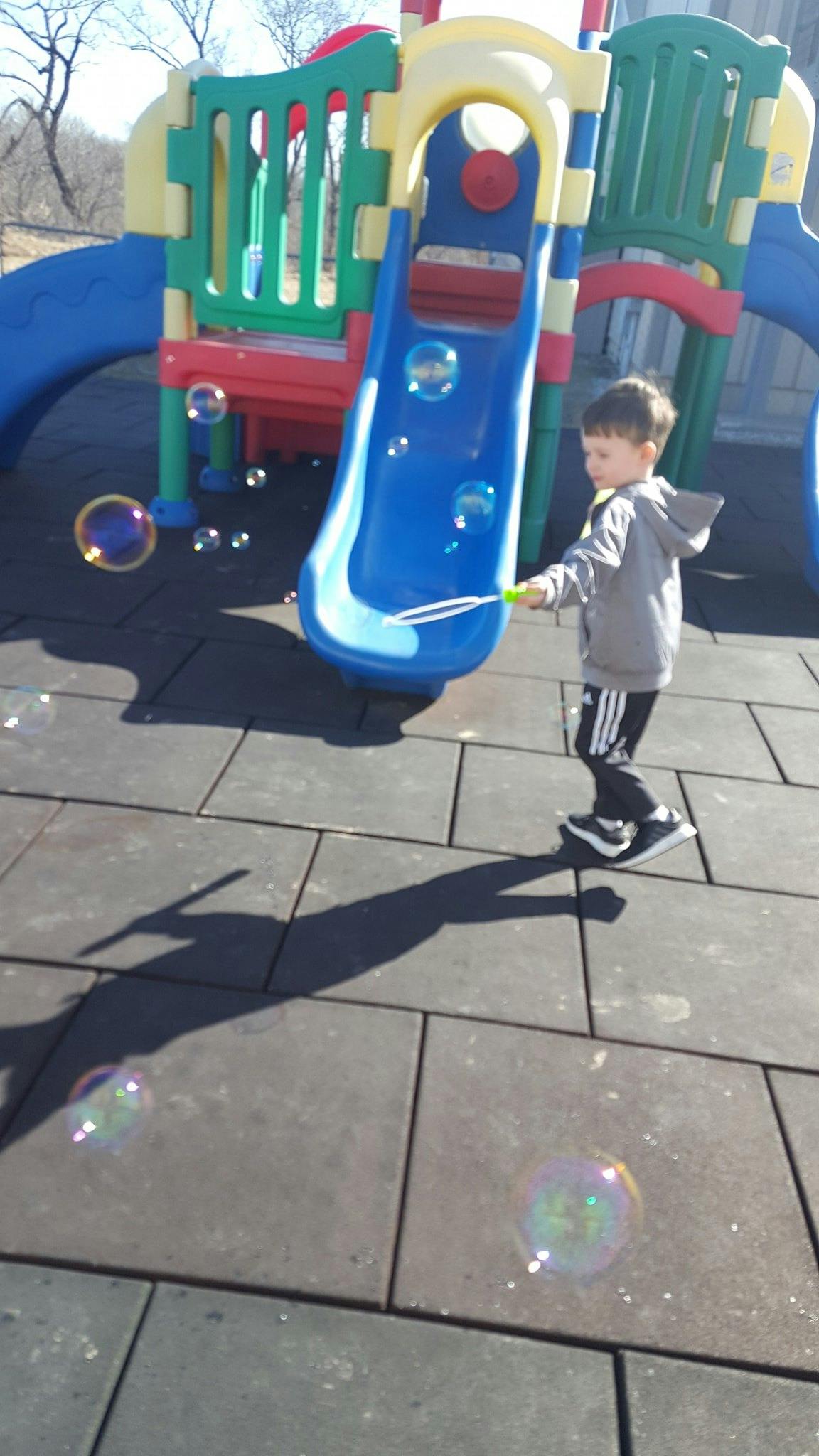 Child blowing bubbles on a playground