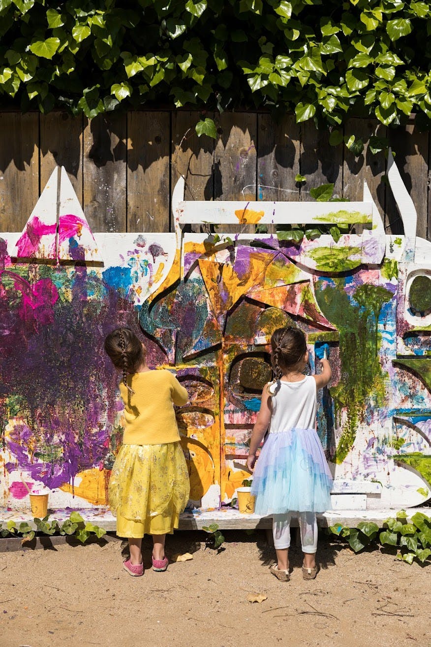 Two children painting on a colorful mural