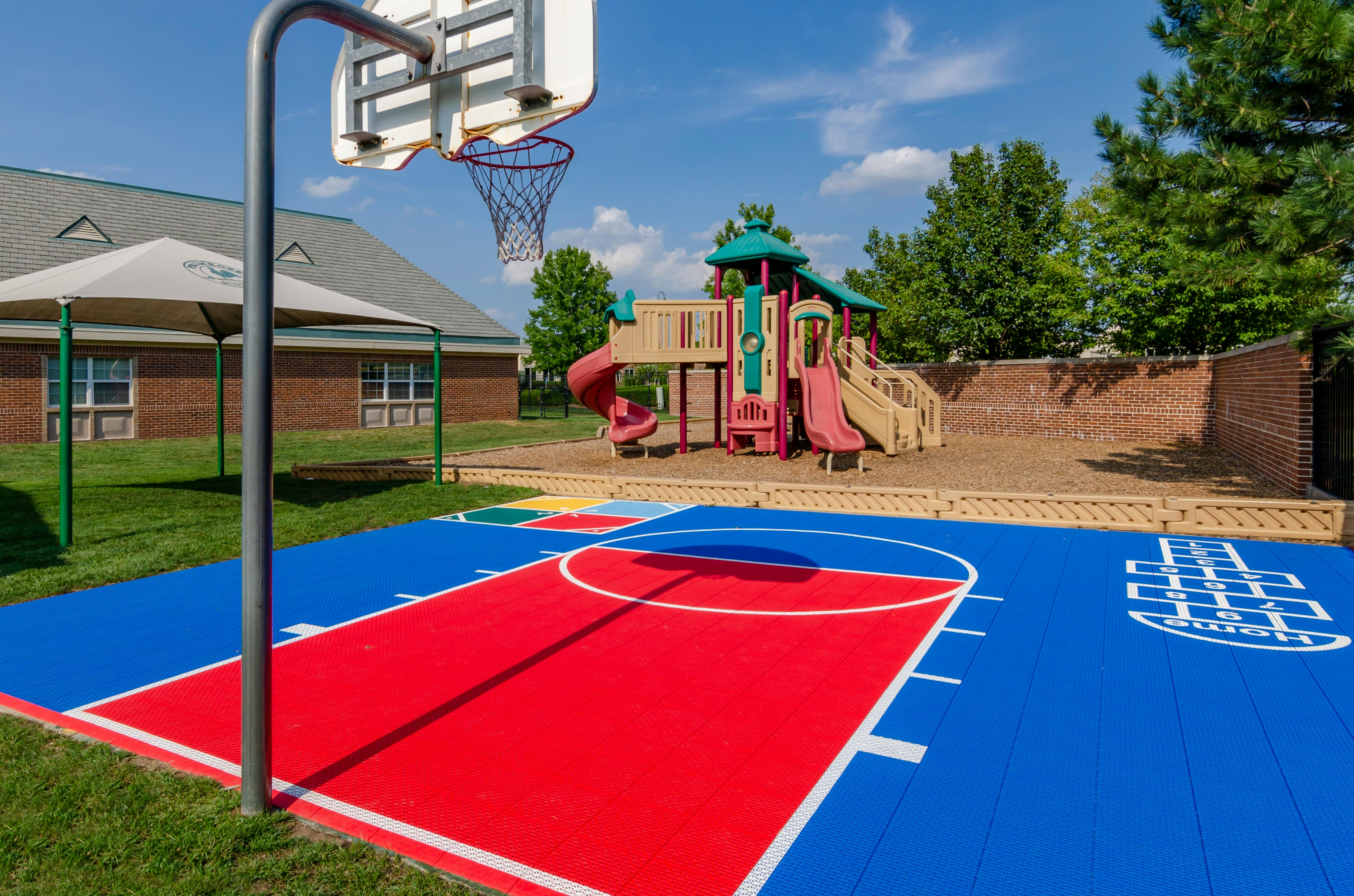 Basketball court with playground and building in the background