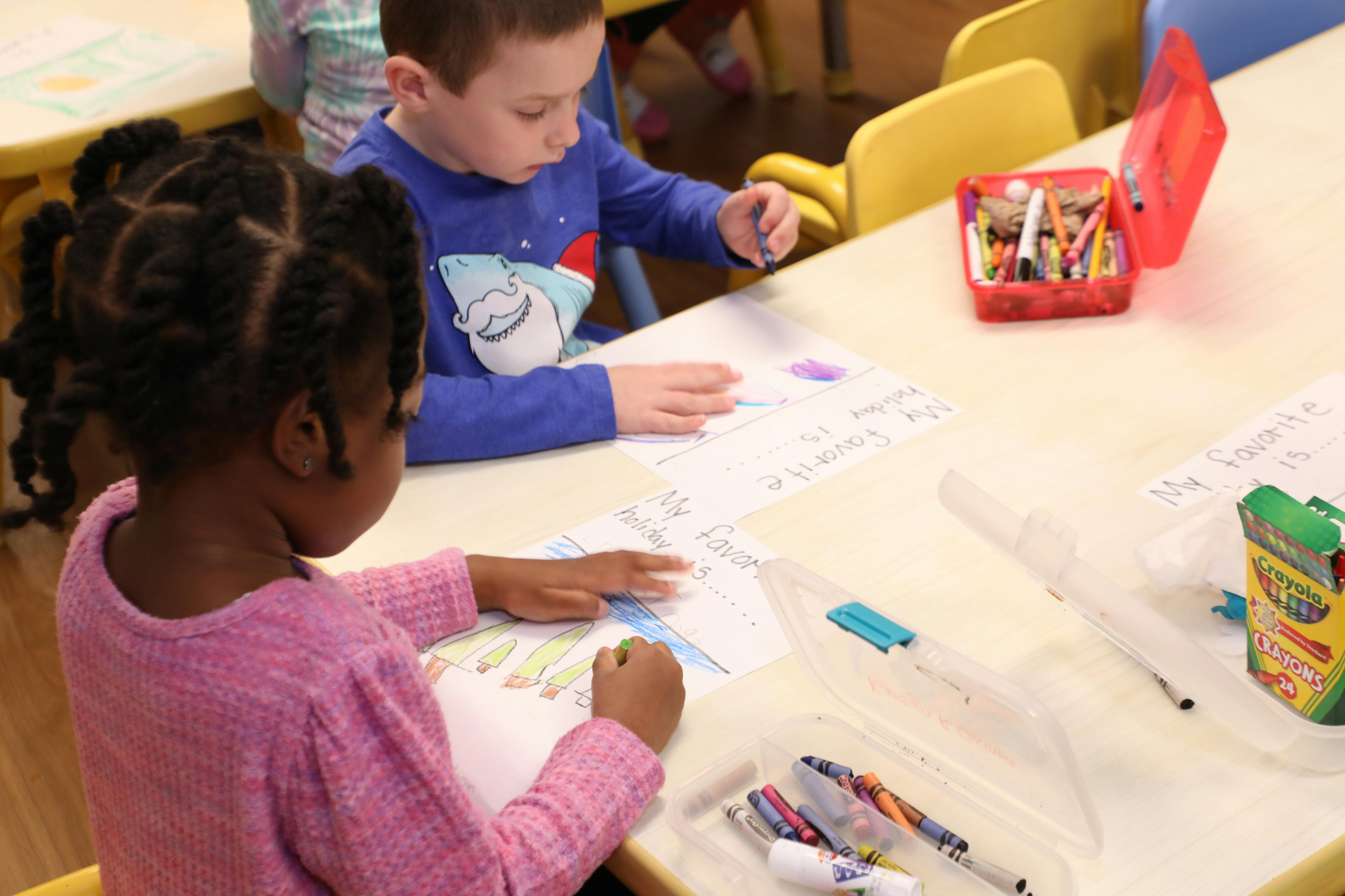 Two children drawing at a table