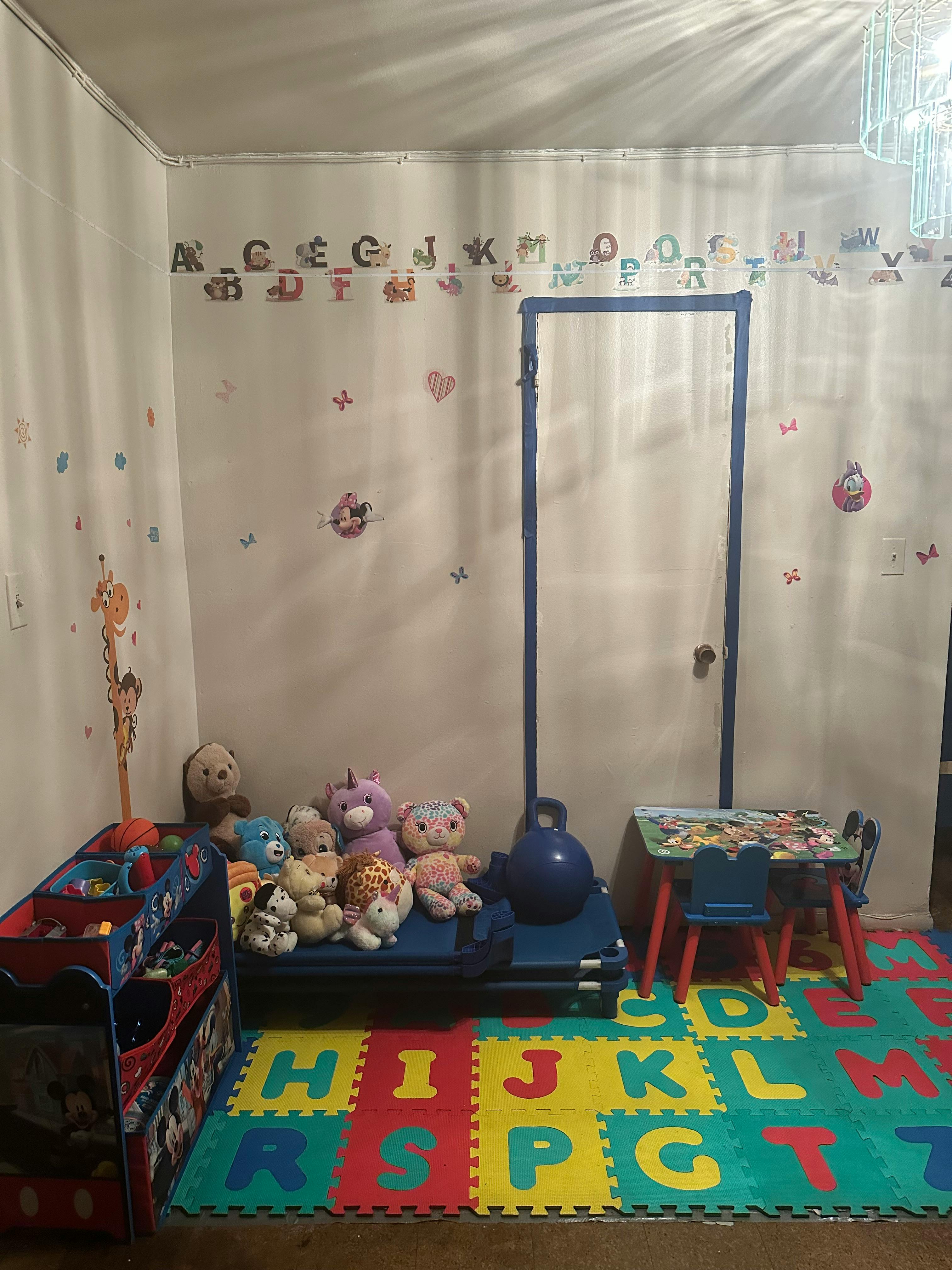 Child's room with alphabet wall decor, stuffed animals, and play mat