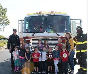 People and children standing in front of a fire truck