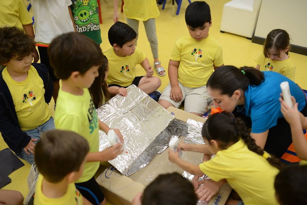 Adult and children working on a craft project with foil