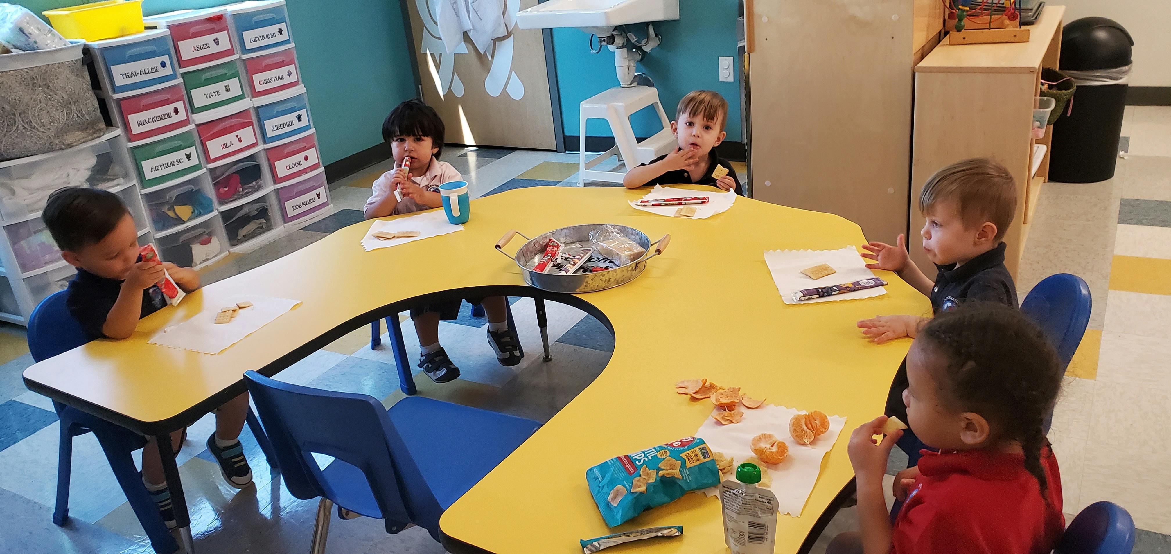 Four children sitting at a yellow table