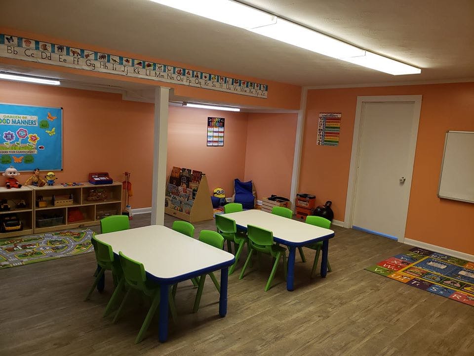 Classroom with small tables and chairs, toys, and educational posters