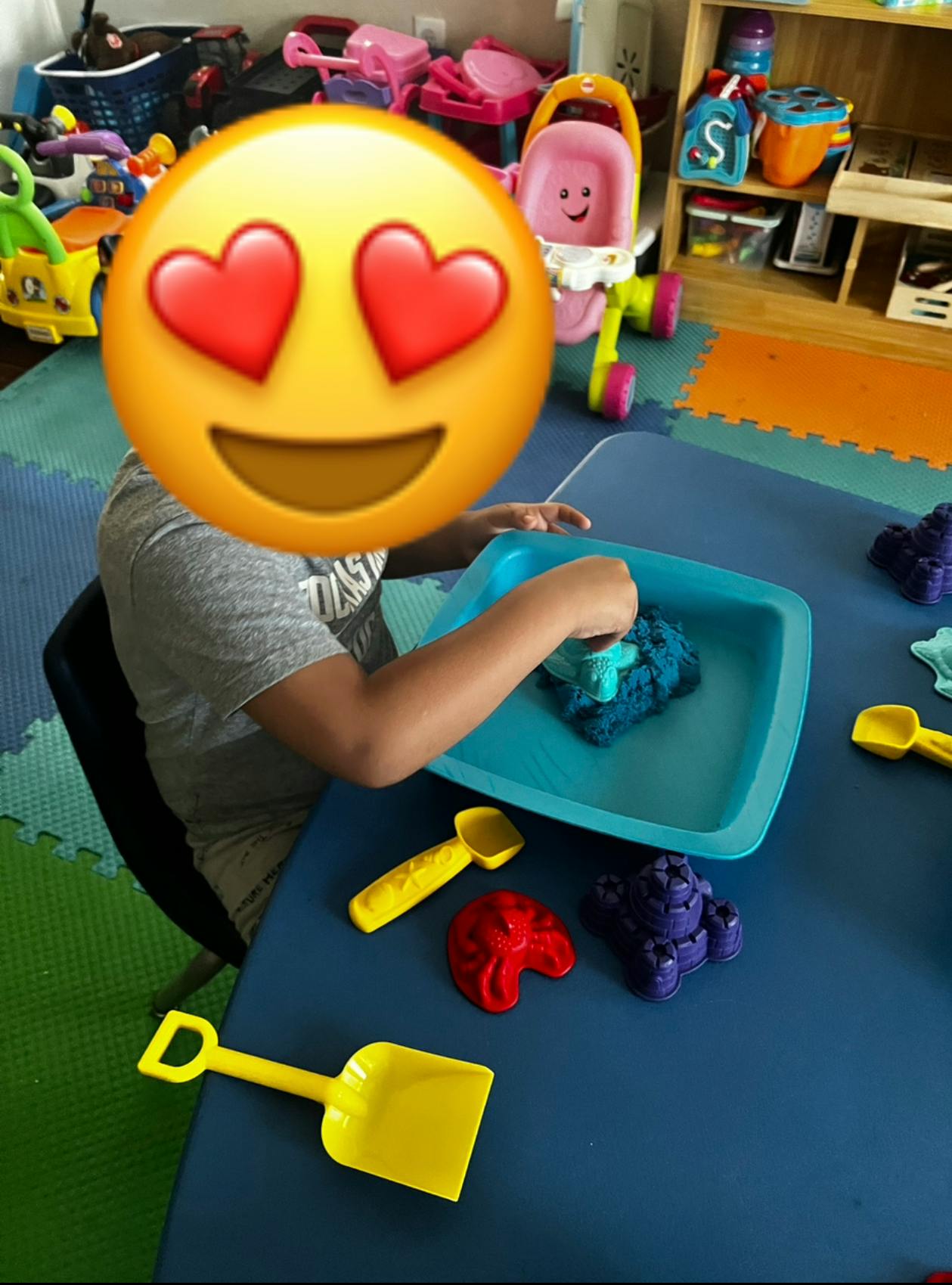 Child playing with kinetic sand and molds at a table