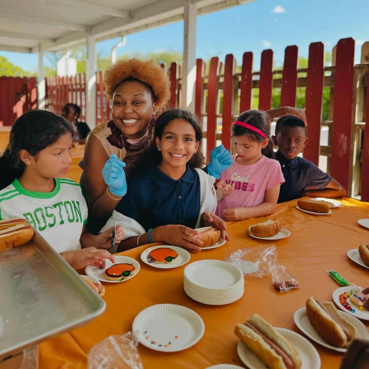 Adult and children sitting at a table with hot dogs and cookies