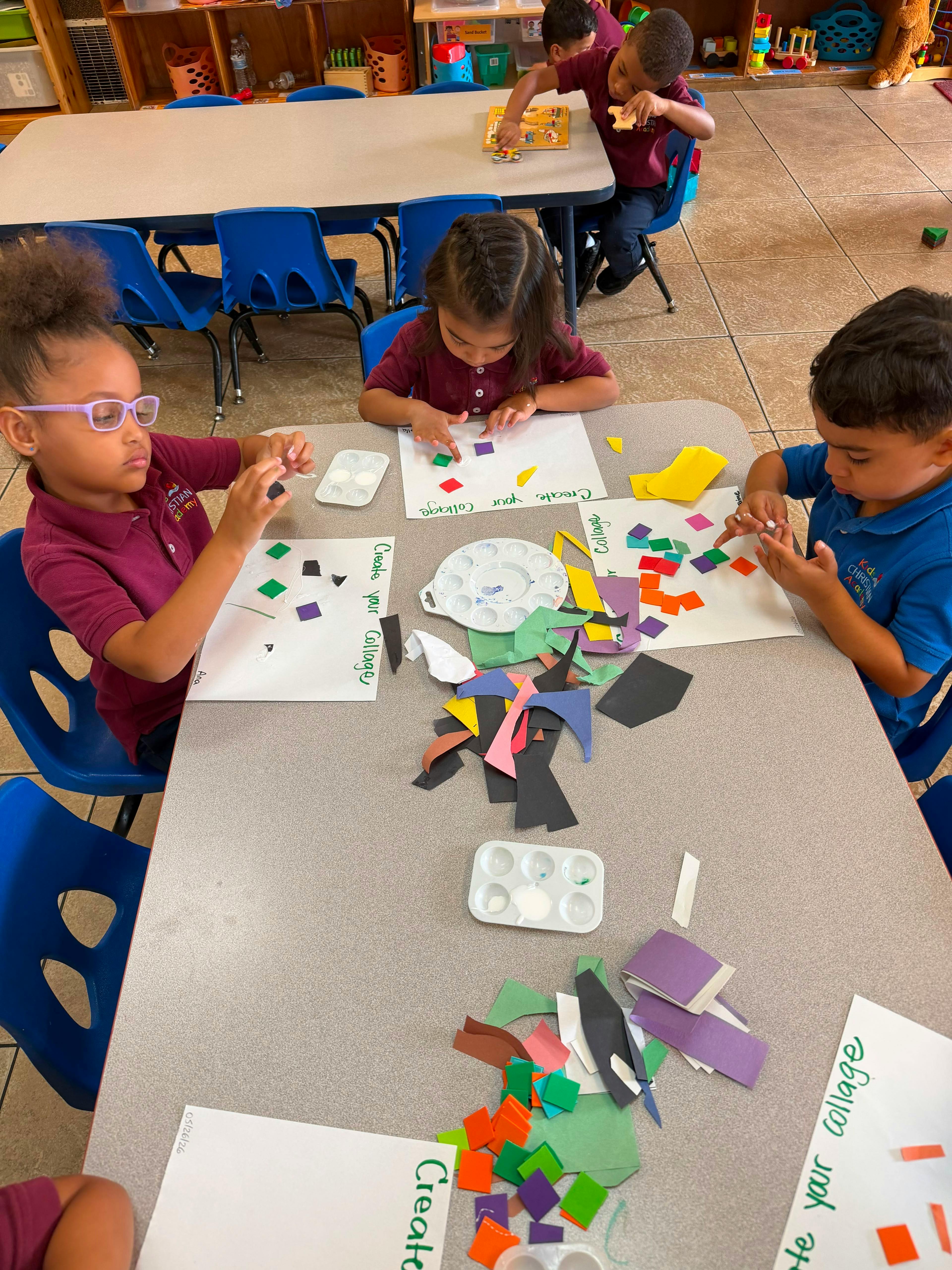 Children sitting at tables creating paper collages in a classroom