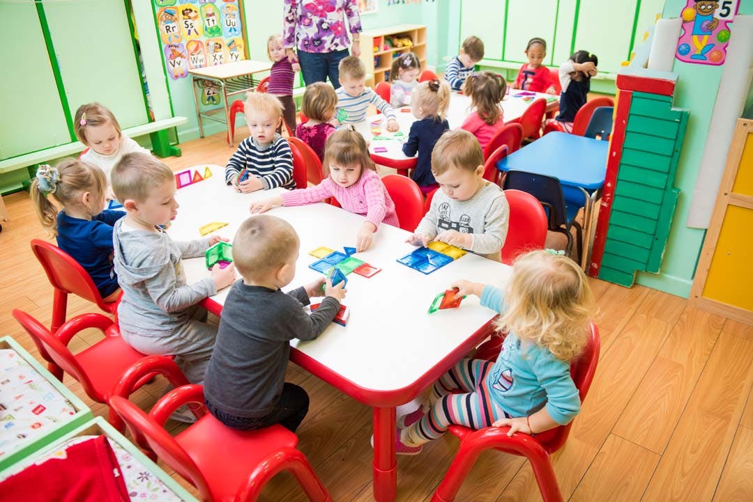 Children sitting at tables and playing with toys in a classroom