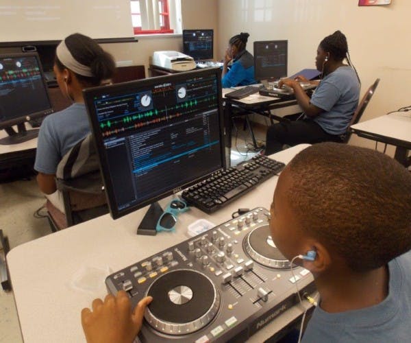 Child using a DJ mixer and computer with audio software
