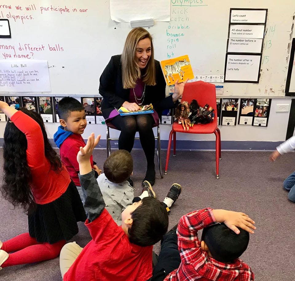Adult reading to children sitting on the floor in a classroom