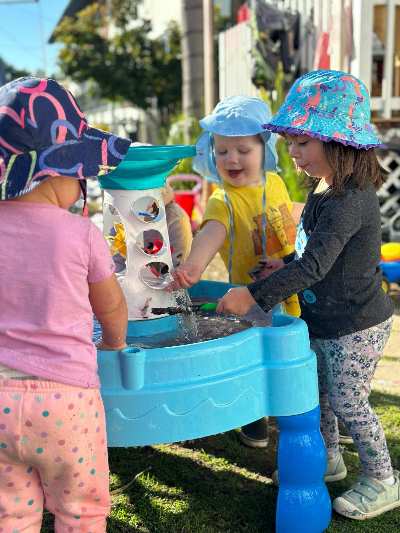 Three children playing with a water table outdoors
