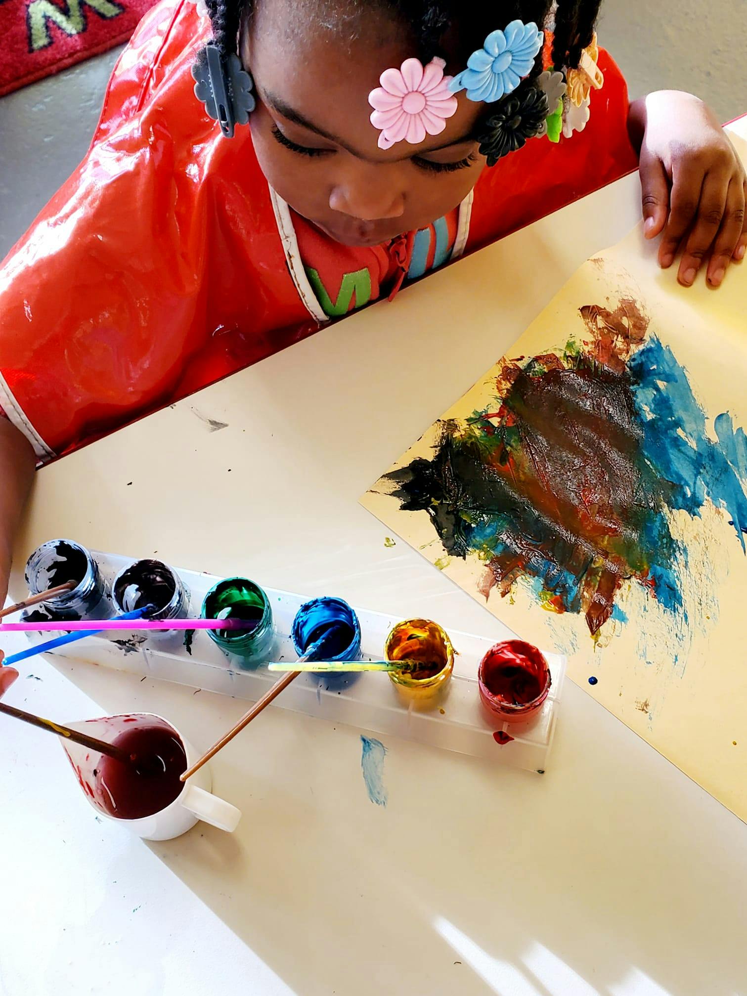 Child painting on paper with various colors