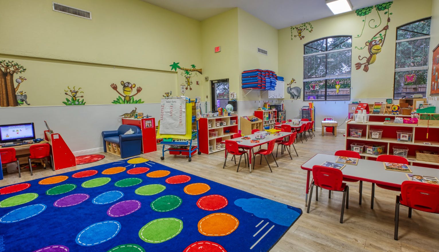 Children's classroom with small tables and chairs, and a colorful rug