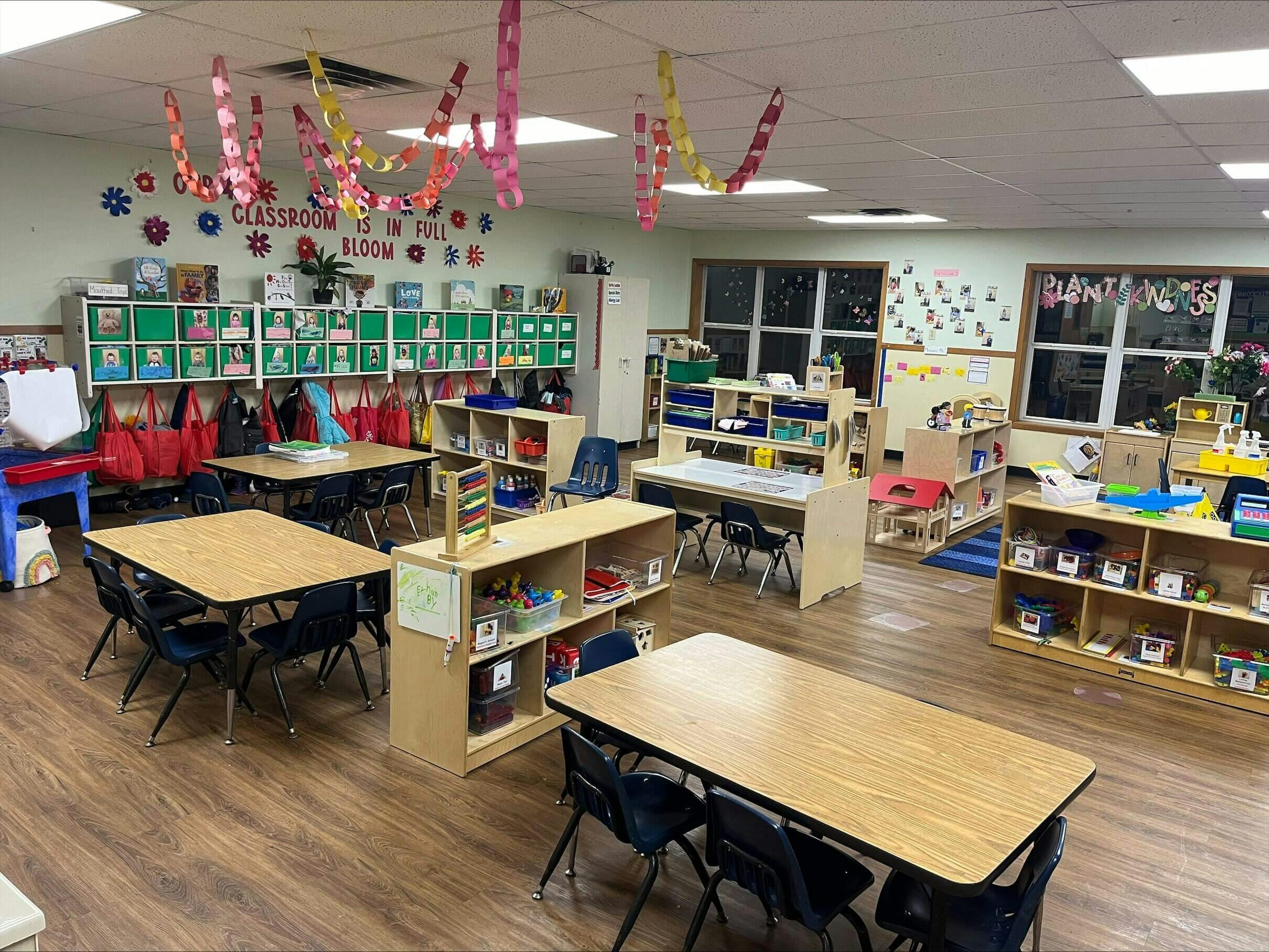 Classroom with child-sized tables and chairs, shelves with toys, and wall decorations