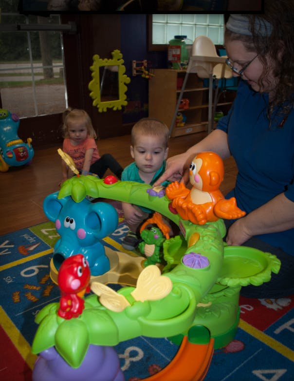 Adult and two children playing with a toy jungle gym