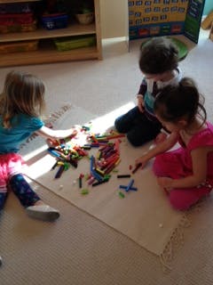 Three children playing with crayons on the floor