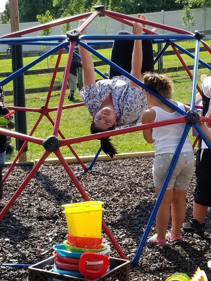 Person hanging upside down on a playground dome climber