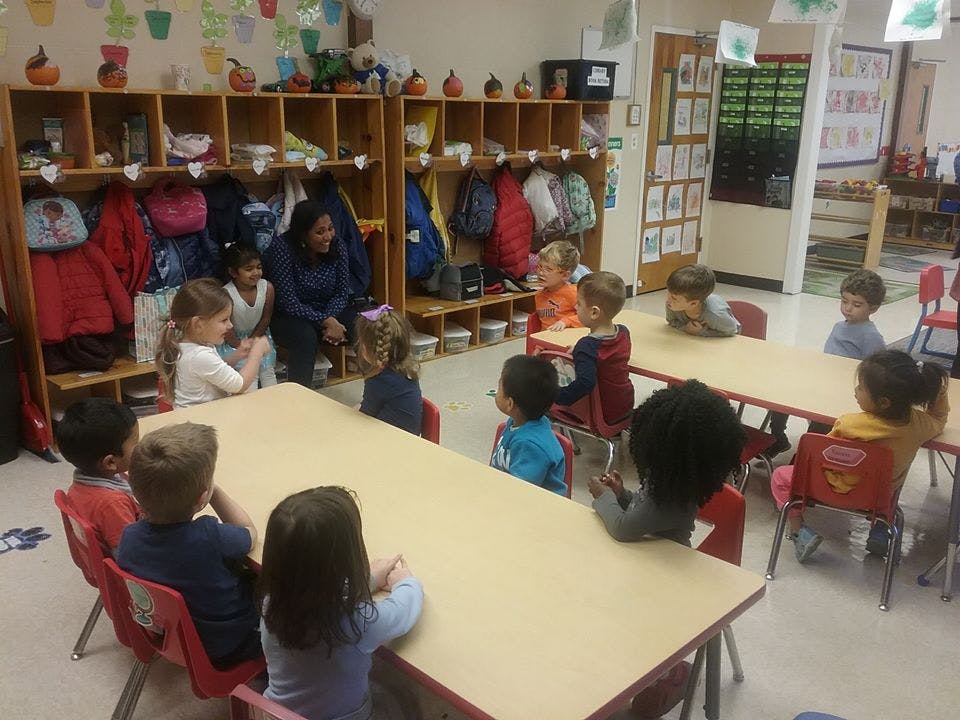 Adult and children sitting at tables in a classroom