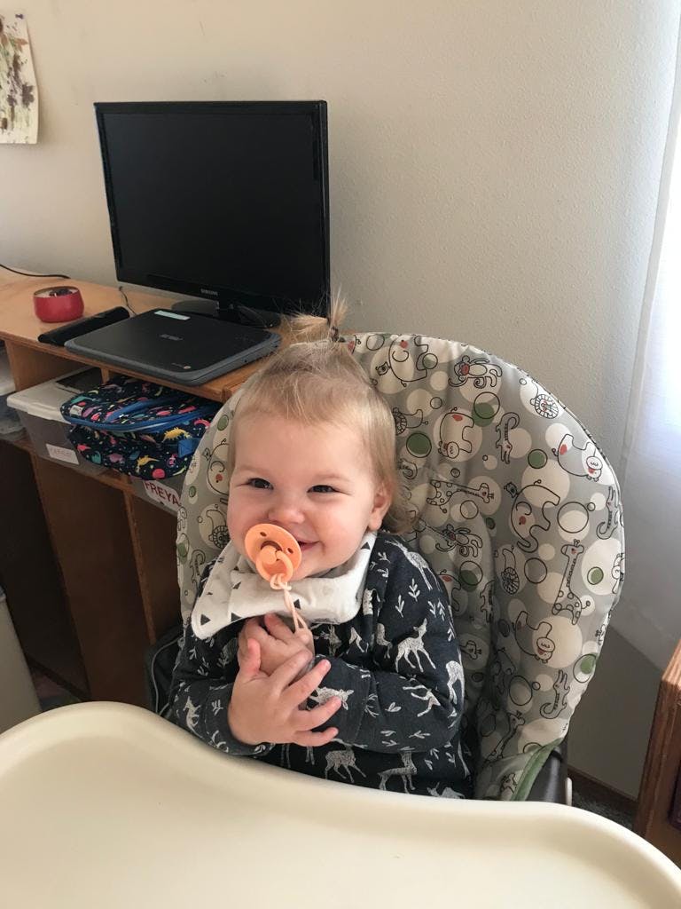 Child in a high chair with a pacifier