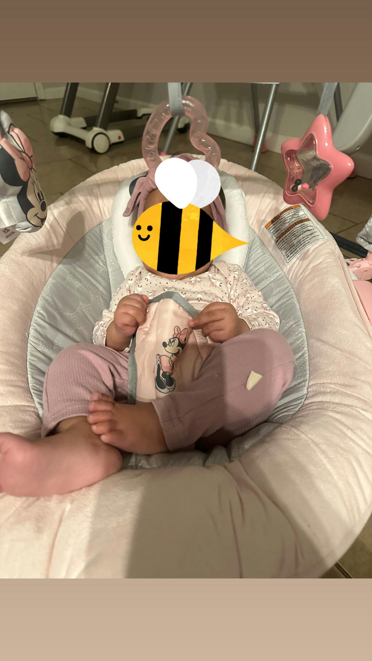 Baby reclining in a baby bouncer seat with hanging toys