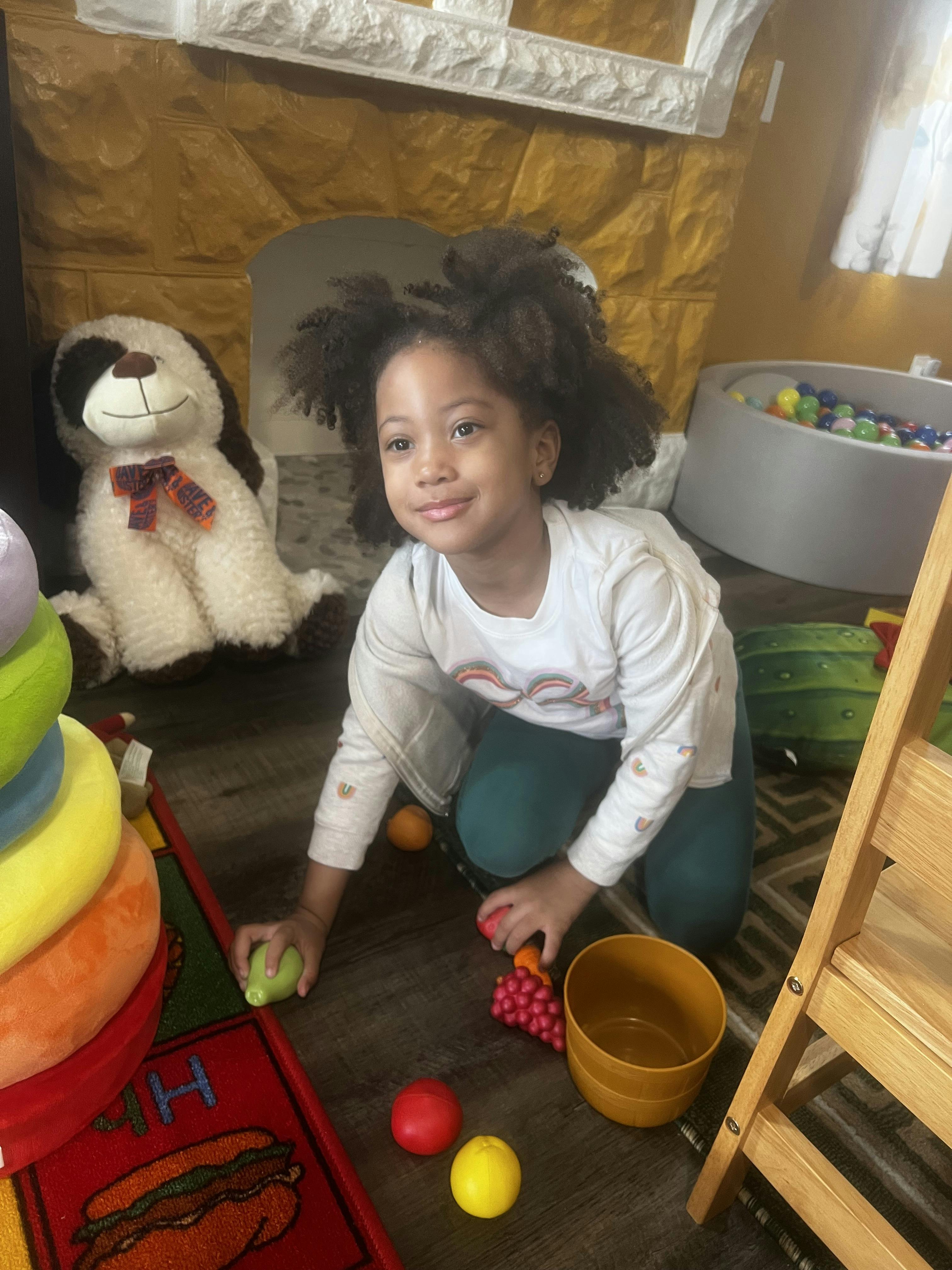 Child crouching on the floor, playing with colorful toys
