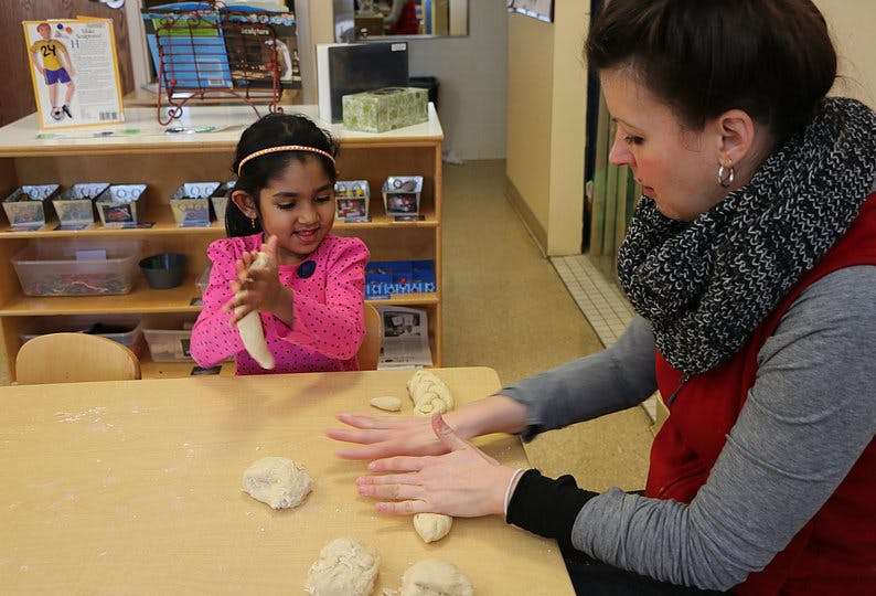 Adult and child rolling dough on a table