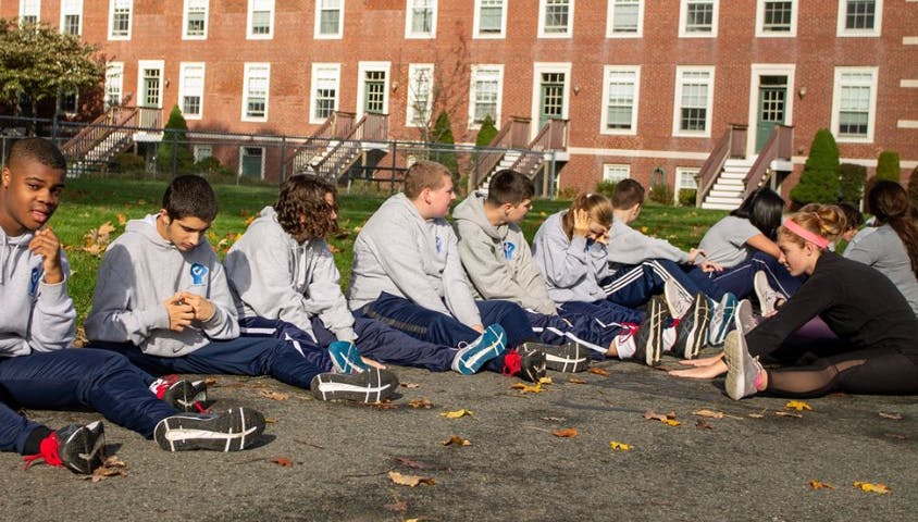 Group of teens sitting on the ground outdoors