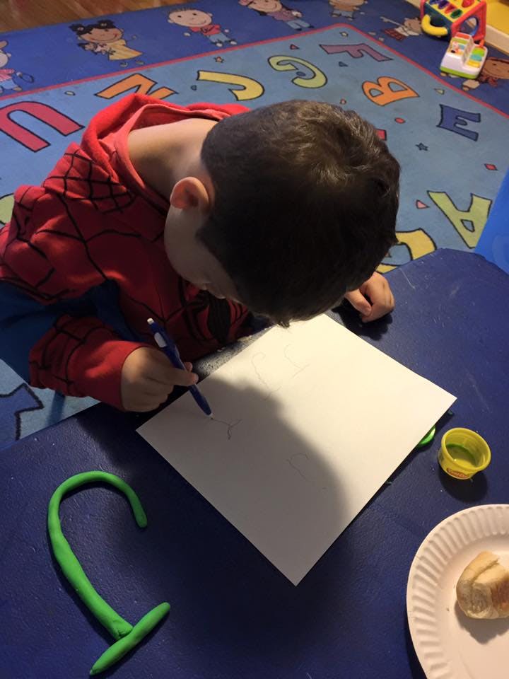 Child drawing on paper with a pen