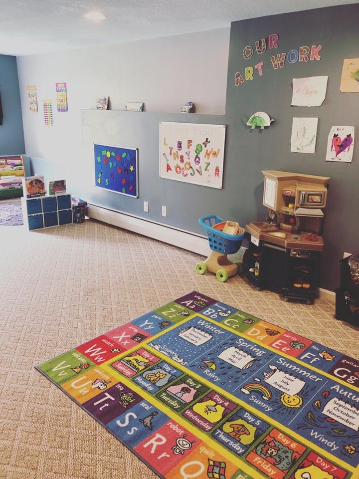 Playroom with alphabet rug, toy kitchen, and children's artwork on walls