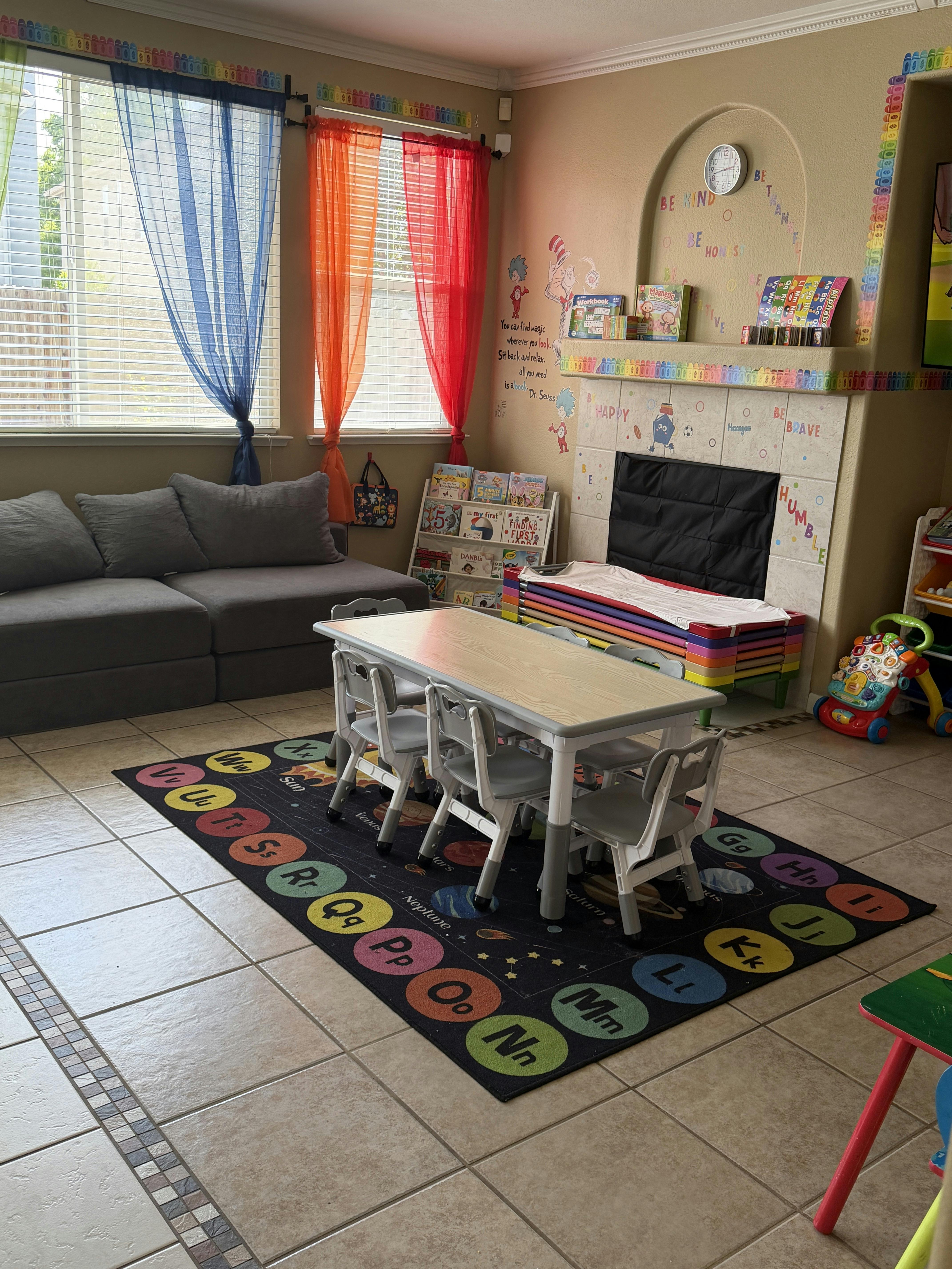 Children's play area with small table, chairs, ABC rug, and book shelves