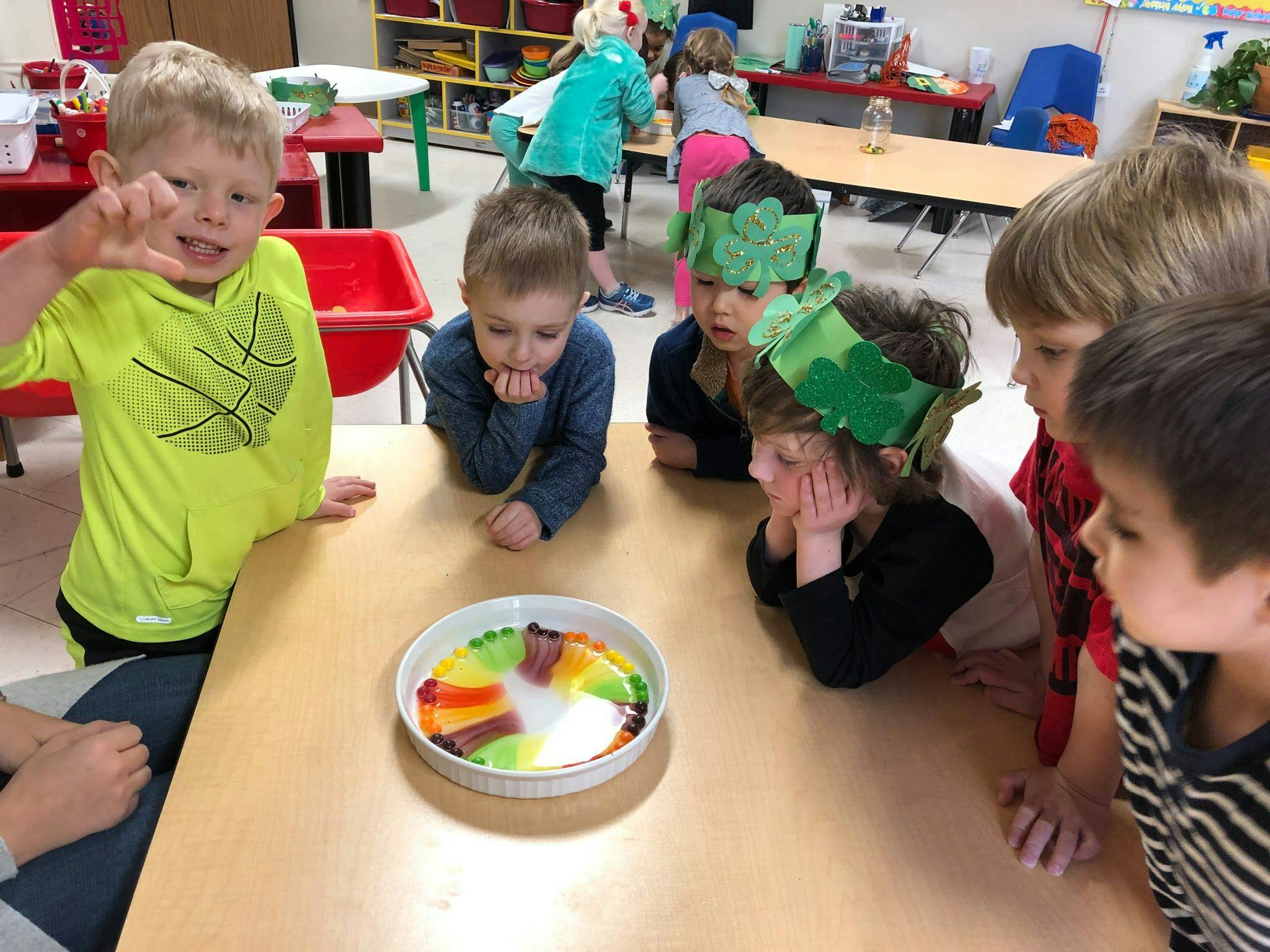 Children gathered around a table watching a science experiment in a dish