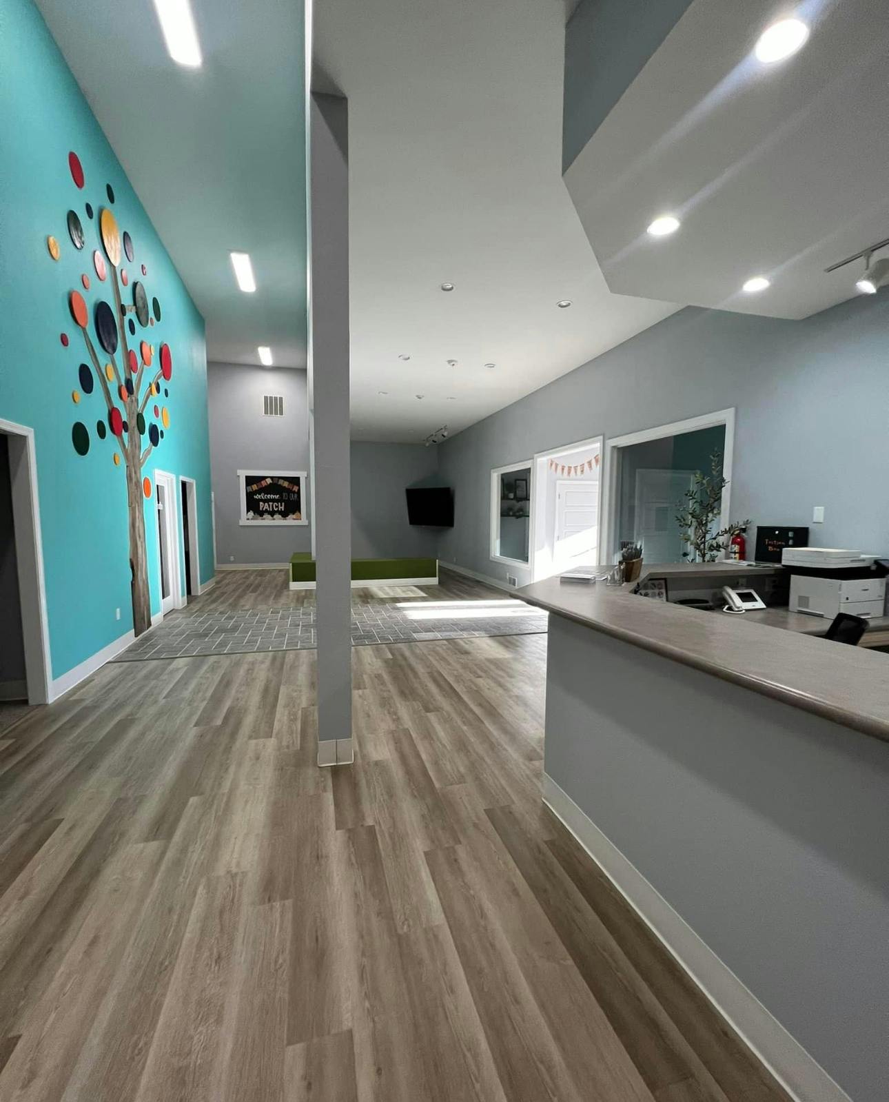 Long hallway with light wood flooring and a teal wall with a tree mural