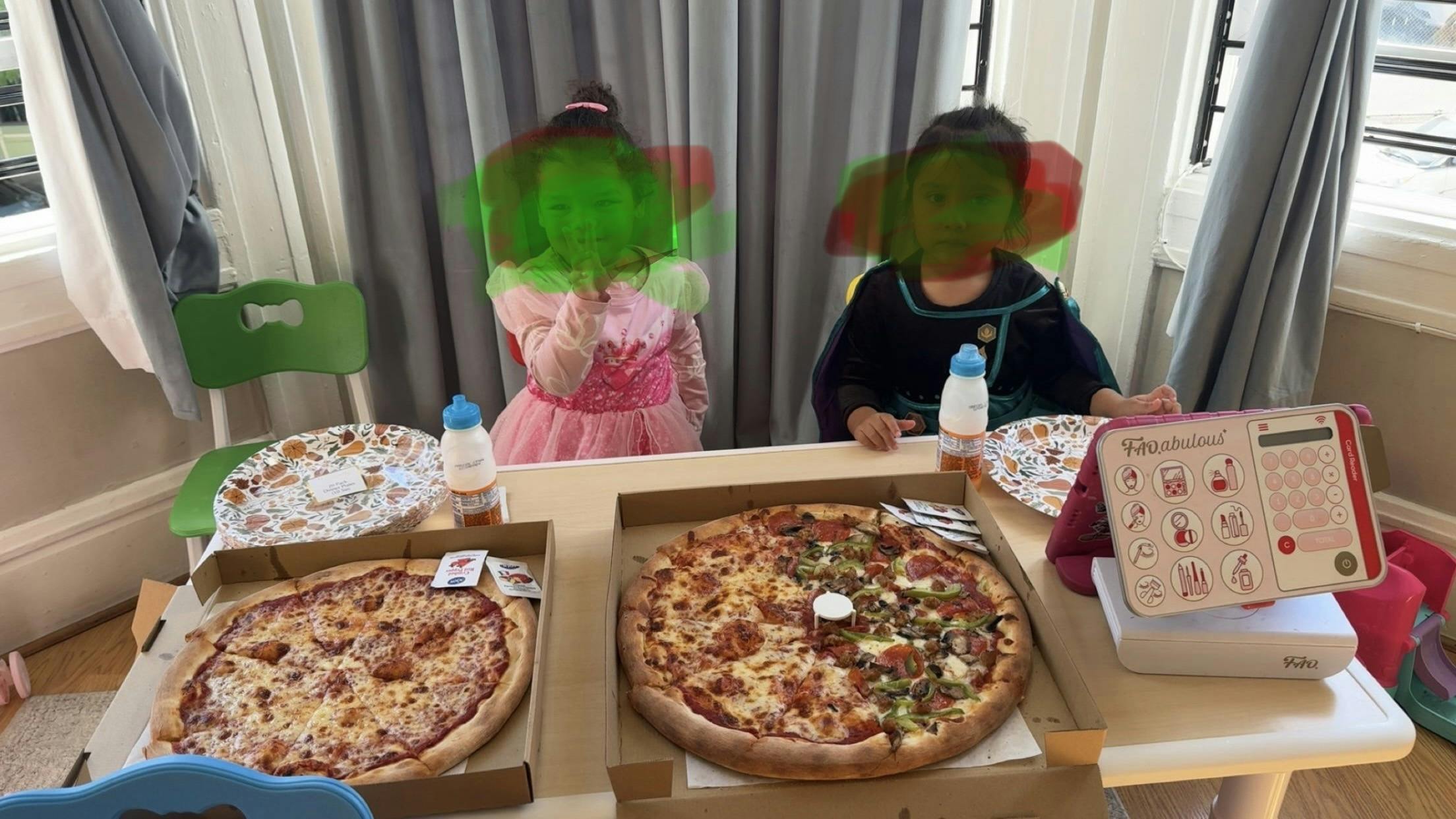 Two children at a table with two pizzas