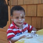 Child with flour on face and hands