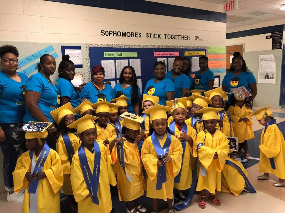 Adults and children in graduation caps and gowns