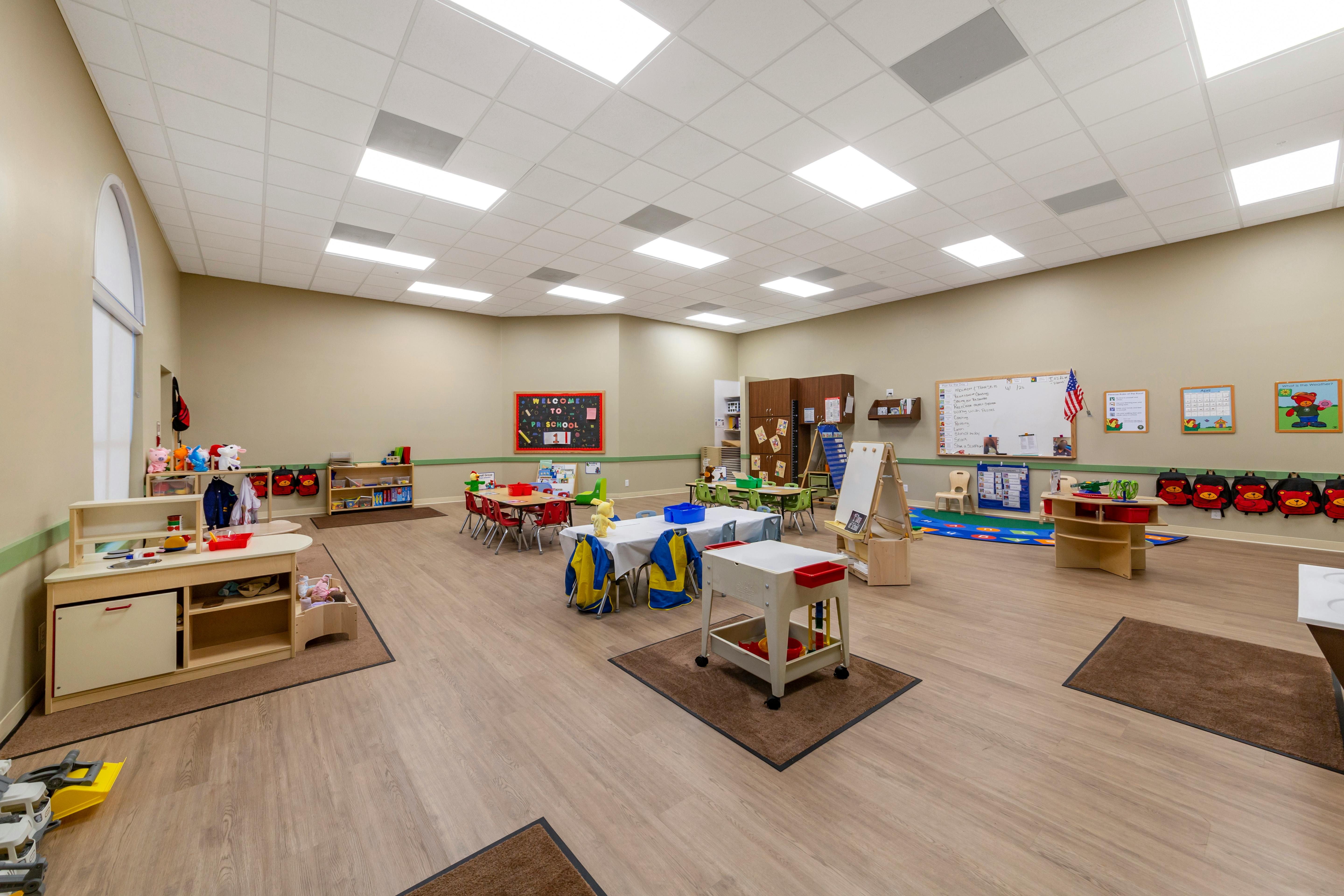 preschool classroom with tables, chairs, and play areas