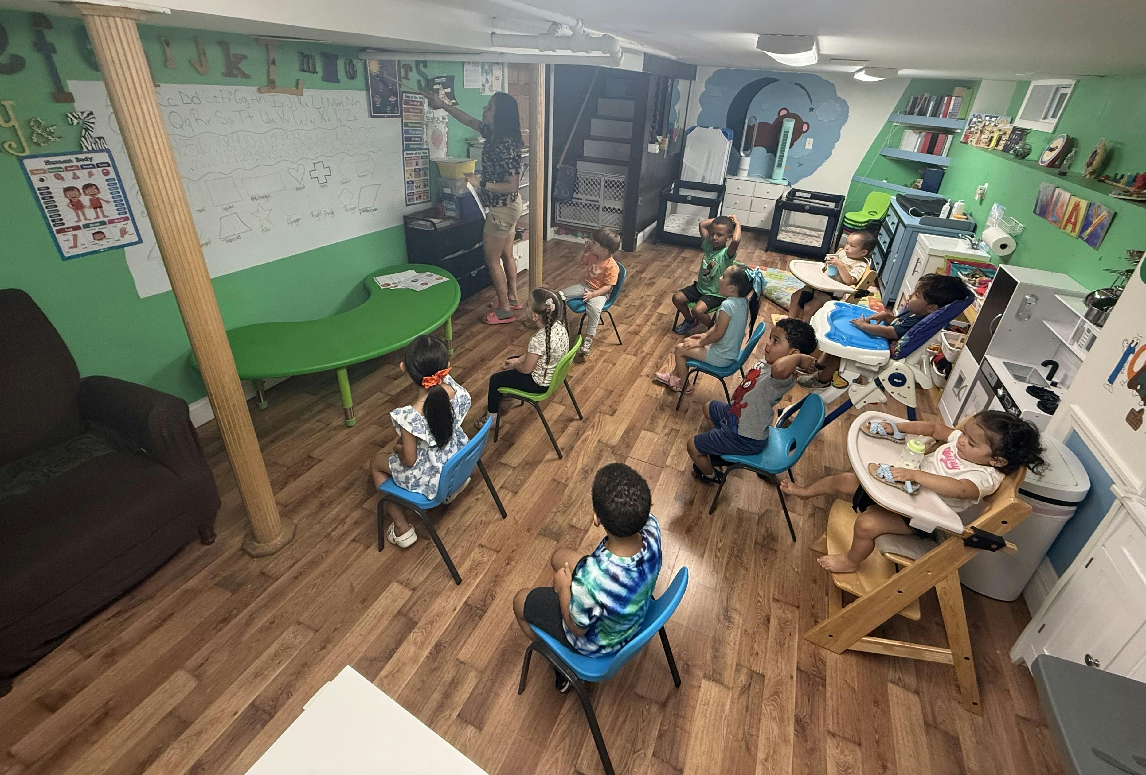 Teacher pointing to a whiteboard while children sit in a classroom