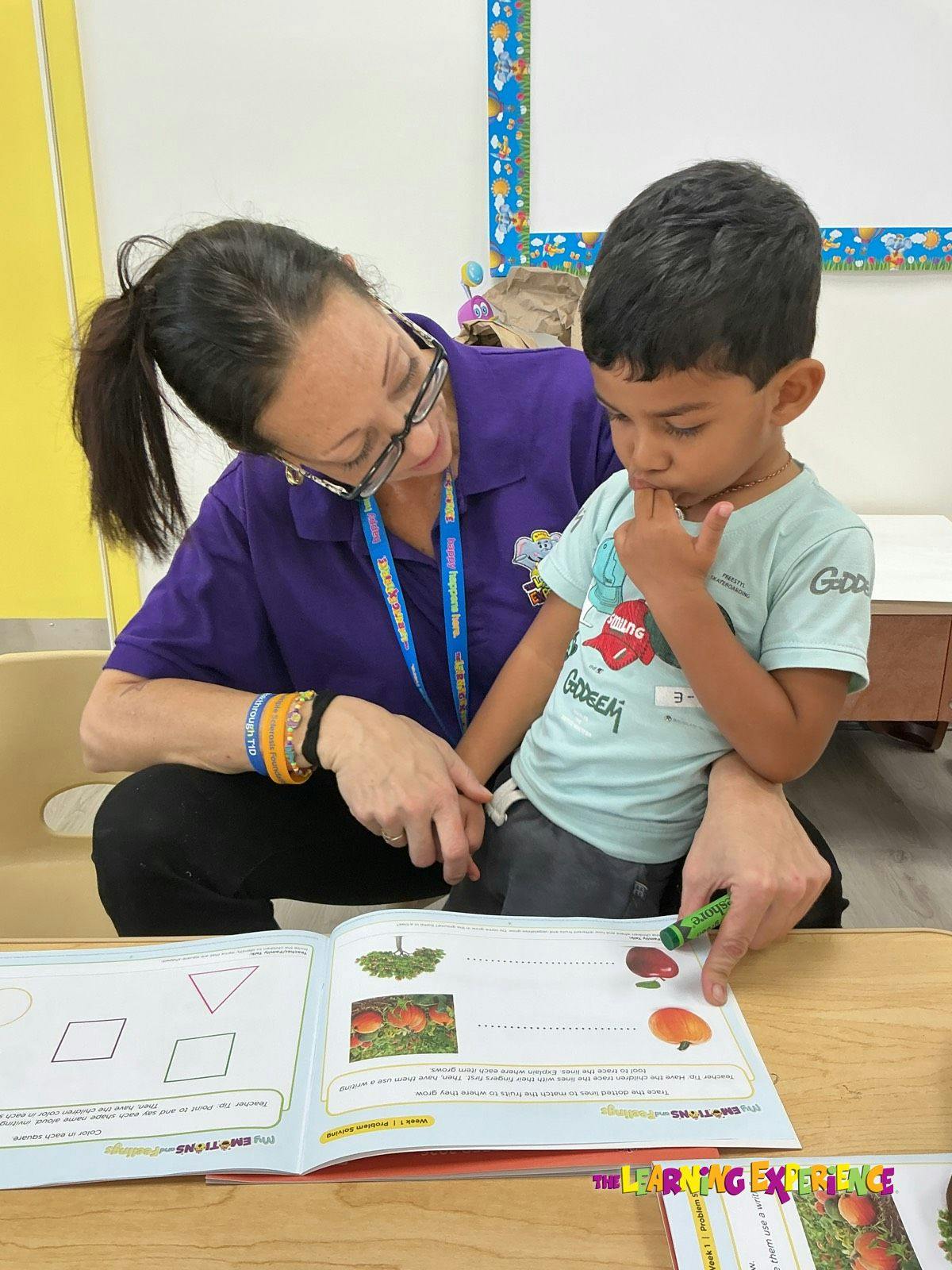 Adult assisting a child with a worksheet in a classroom