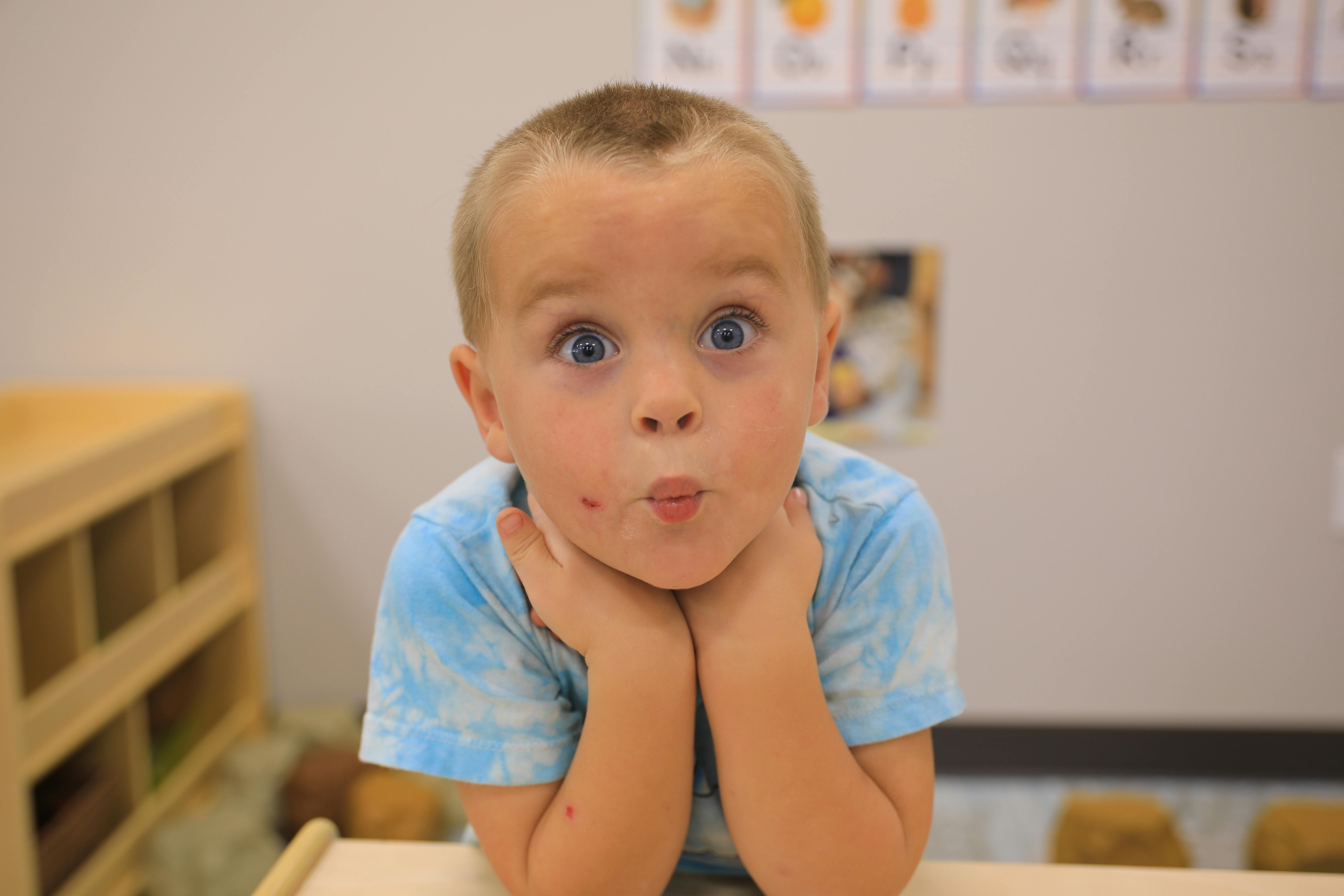 Child with hands under chin making a surprised face