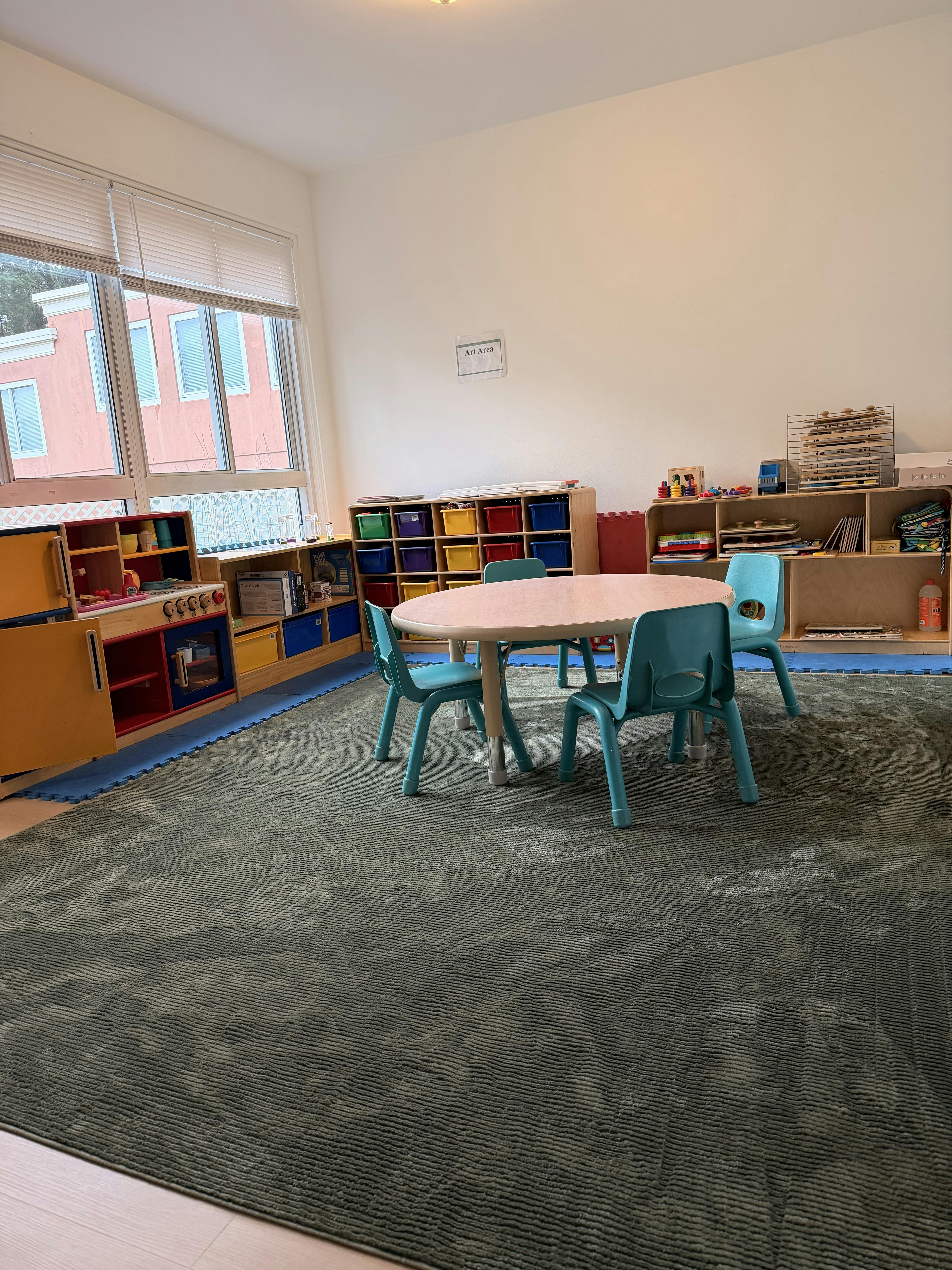 Classroom with small table and chairs, toy kitchen, and storage shelves
