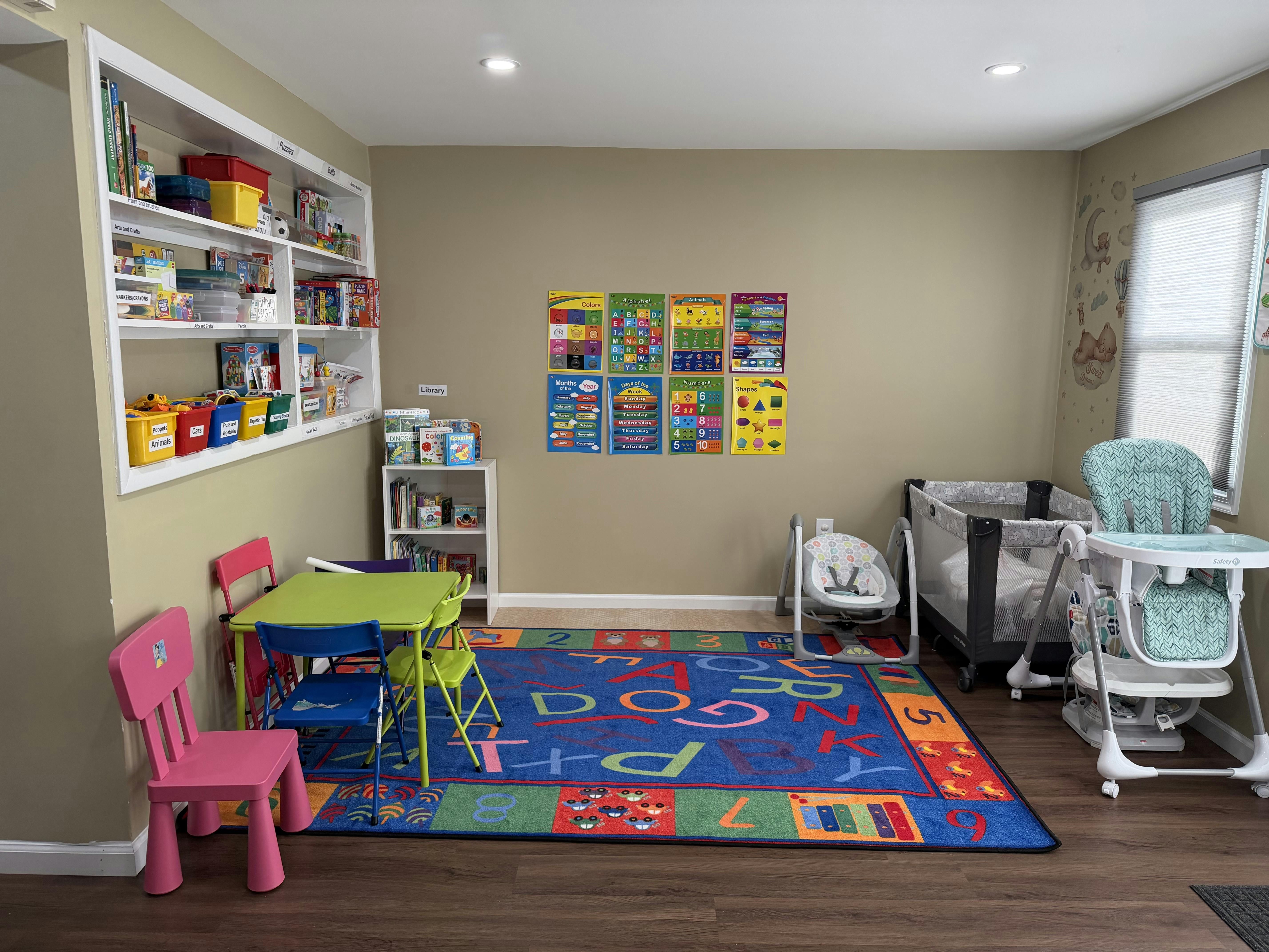 Child's playroom with alphabet rug, small table and chairs, crib, and high chair