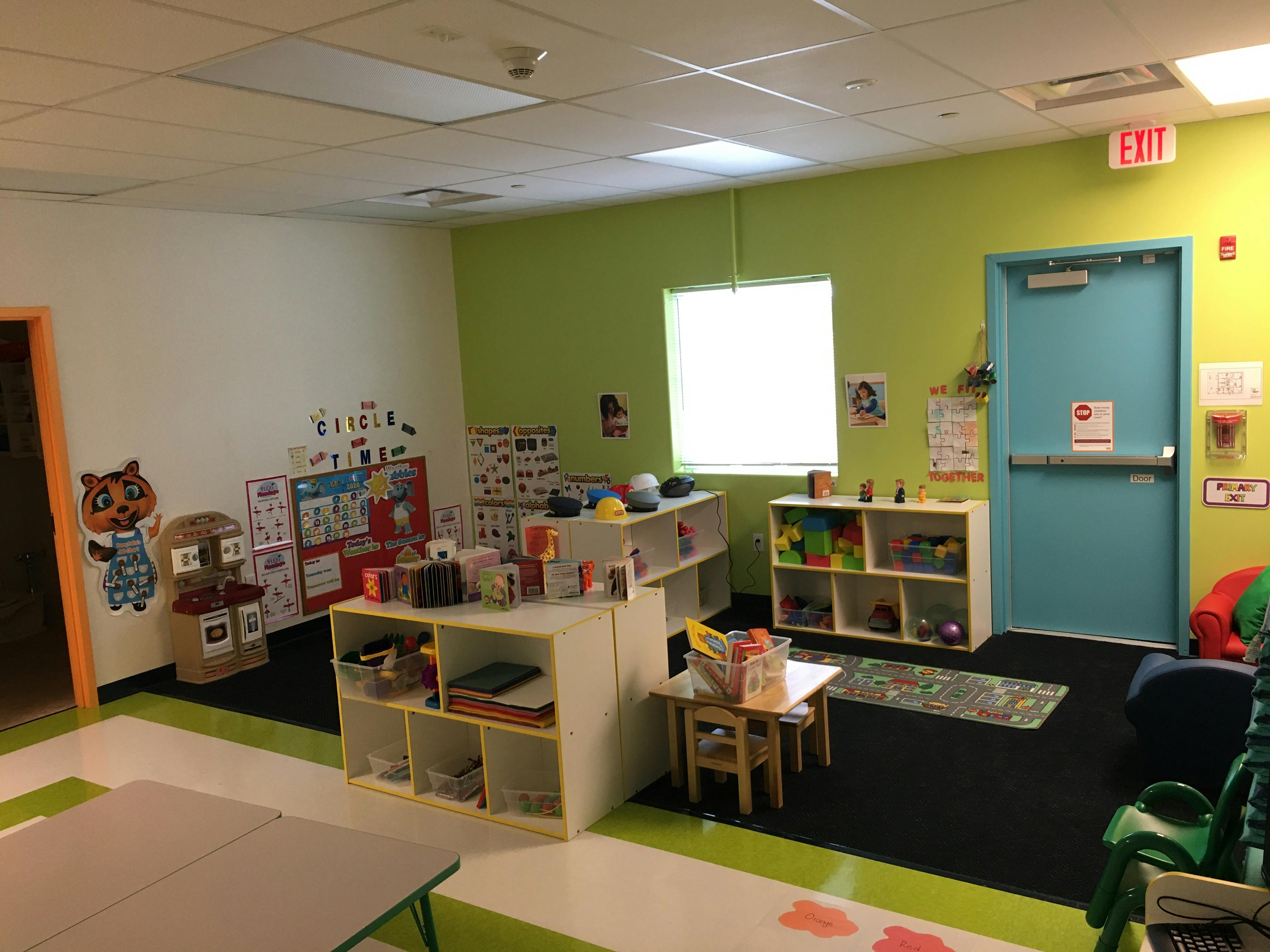Classroom with green walls, shelves, and small tables