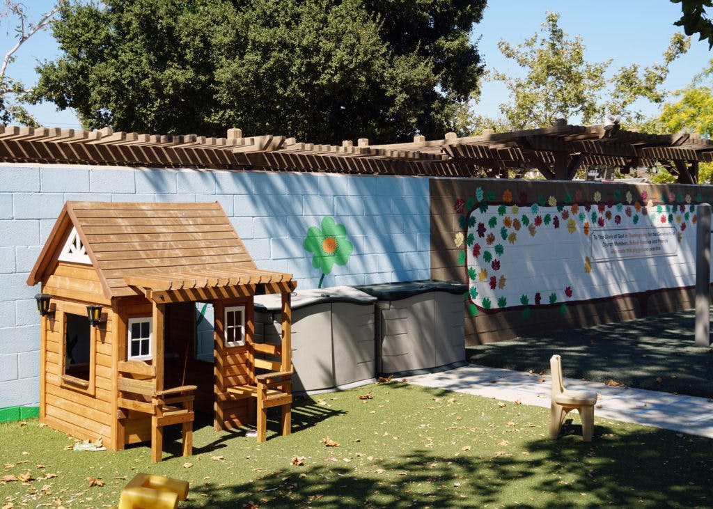 Wooden playhouse on artificial grass next to a painted wall
